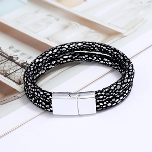 Detail of double-layer black braided leather bracelet with silver accents and magnetic clasp
