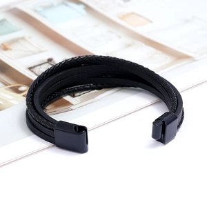 Détail d'un bracelet multicouche en cuir tressé noir avec fermoir magnétique
