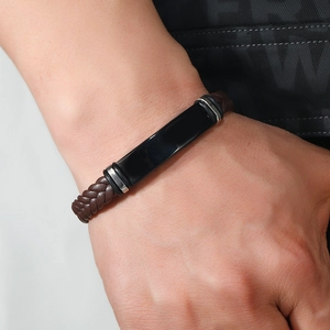 Detalle de la pulsera de cuero trenzado marrón con placa de metal negro para hombres