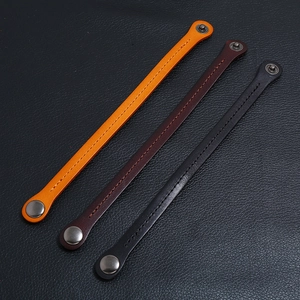 Detail of minimalist leather bracelets in black, brown and orange with metal snaps