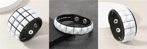 Detailansicht von Punk-Lederarmbändern mit weißen quadratischen Nieten und Druckknöpfen