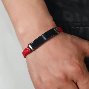 Primer plano de pulsera trenzada de cuero rojo para hombre con placa metálica negra al detalle