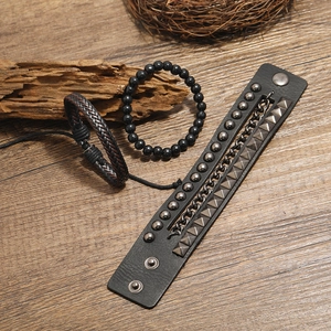 Vintage woven leather bracelet set with beads and metal studs on wooden background