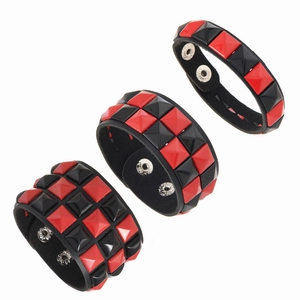 Detail von Punk Lederarmbändern mit roten und schwarzen quadratischen Pyramidennieten