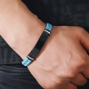 Detalle de una pulsera trenzada azul claro para hombre con placa metálica negra