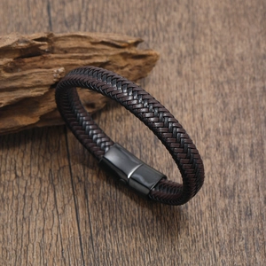 Men's woven leather bracelet with matte black magnetic clasp on rustic wood background