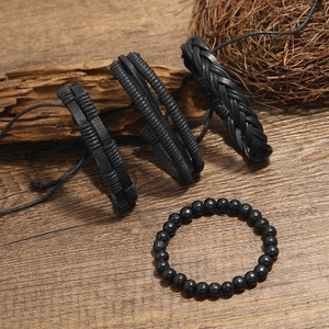 Retro black leather braided bracelet set with four pieces on a rustic wooden background