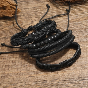 Set of 4 vintage black leather braided and beaded bracelets on a natural wood surface