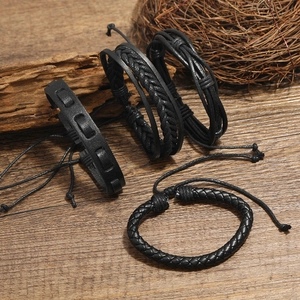 Set of four vintage black braided leather bracelets for men on a rustic wooden background
