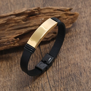 Detalle de una pulsera de cuero para hombre con placa de metal dorada sobre madera