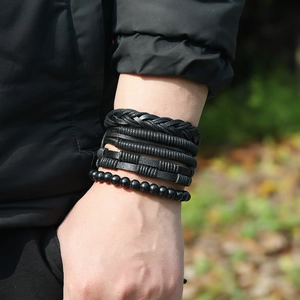 Macro shot of a layered black leather bracelet set featuring braided and beaded styles on wrist
