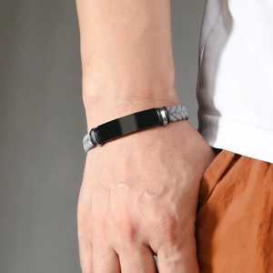 Detalle de pulsera trenzada para hombre con placa de metal negro pulido en la muñeca