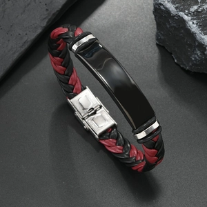 Detalle de pulsera de cuero trenzado con cierre grabado de acero inoxidable en negro y rojo