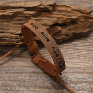 Vintage braided brown leather bracelet with bronze metal chain on wooden background