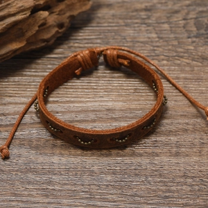 Detail view of retro braided leather bracelet with metal beads on a rustic wooden background
