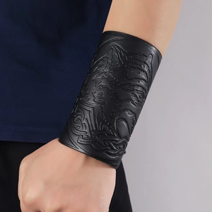 Detailed macro view of the embossed wolf head and Celtic patterns on the black leather bracer