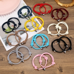 Close-up of colorful braided couple bracelets with magnetic heart clasps on a wooden table