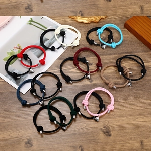 Close-up of adjustable woven couple bracelets with magnetic heart clasps on wood