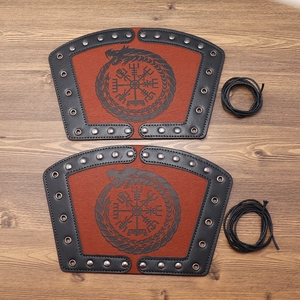 Brown Viking leather bracers with Vegvisir compass and metal rivets on wood background