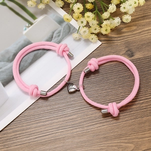 Close-up of pink woven couple bracelets with magnetic heart closure and adjustable knots