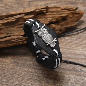 Bracelet fait main en cuir noir avec breloque chouette sur fond en bois rustique