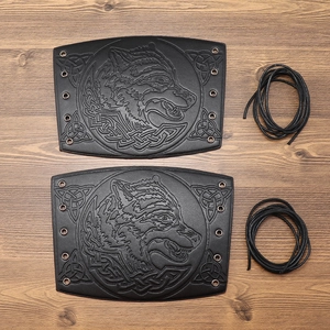 Detail of Viking wolf head embossing on black leather gauntlets with Celtic knot designs
