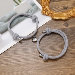 Close-up of light grey braided couple bracelets with magnetic heart-shaped charms