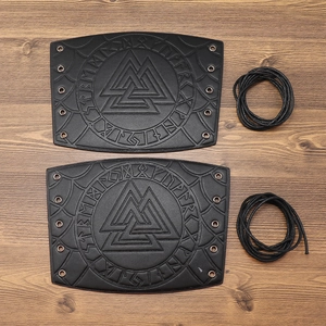Detail of Viking leather arm guards with Valknut symbol and lace-up straps on wood