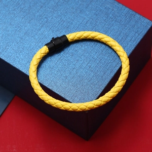 Détail du bracelet tressé jaune en cuir avec fermoir magnétique noir mat sur coffret
