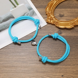 Close-up of blue braided couple bracelets with a silver magnetic heart-shaped clasp