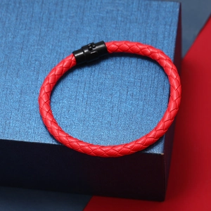 Détail d'un bracelet en cuir tressé rouge avec fermoir magnétique noir sur boîte