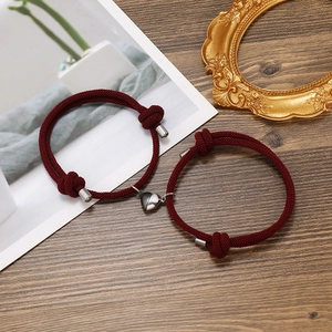Close-up of wine red braided couple bracelets with heart-shaped magnetic clasp closure