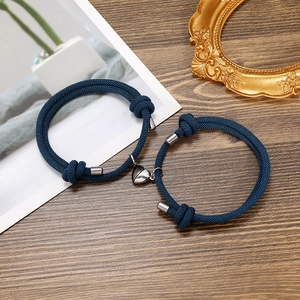Detail shot of navy braided rope couples bracelets with magnetic heart-shaped pendants