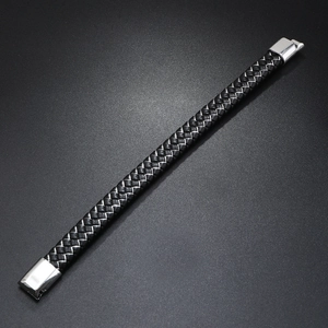 Close-up of woven black leather bracelet with a polished silver magnetic clasp on dark surface