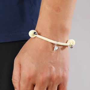 Close-up of cream woven rope bracelet with heart magnet charm and silver metal finish