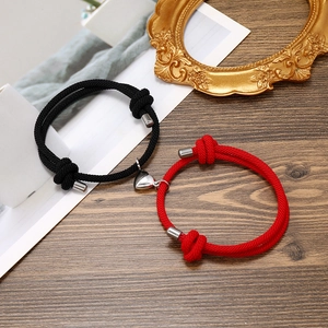 Close-up of magnetic heart charms on red and black braided adjustable couple bracelets
