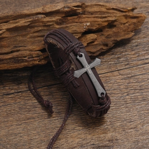 Gros plan du bracelet vintage en cuir tressé marron avec un pendentif croix en métal