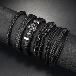 Detail of layered black braided leather men's bracelets with vintage silver cross charm