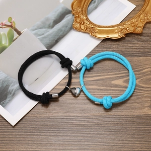 Close-up of black and blue braided couple bracelets with magnetic heart charm