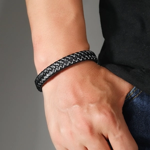 Detailed close-up of men's multi-strand black woven leather bracelet with silver stitching