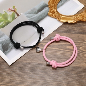 Close-up of woven heart magnetic couple bracelets with pink and black braided ropes