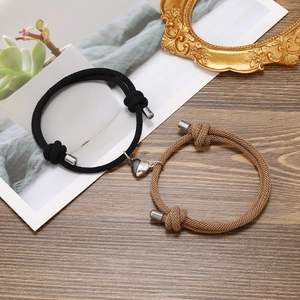 Detail shot of black and brown woven heart magnet couple bracelets on a wooden surface