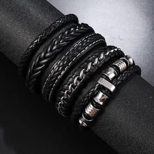 Detail view of multi-layer men's leather bracelets with braided straps and metal charms