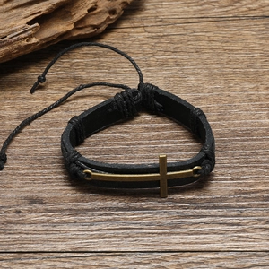 Bracciale vintage da uomo in pelle con croce di bronzo su fondo di legno scuro
