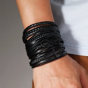 Detail of men's multilayer braided leather bracelet with infinity and cross charms