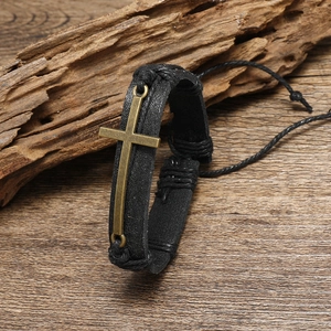 Bracciale vintage in pelle intrecciata uomo con croce in bronzo su fondo legno rustico