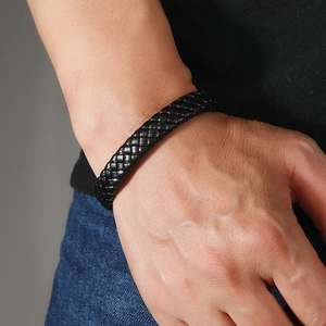 Detail of men's black leather woven bracelet with copper metal accents on model