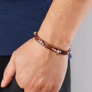 Detail eines Vintage Lederarmbands in Braun mit Perlen und Metallnieten am Handgelenk