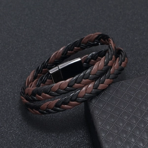 Close-up of woven leather bracelet with polished black magnetic clasp on textured background