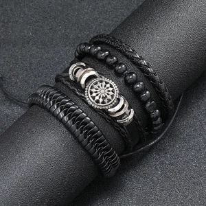 Macro detail of men's layered leather bracelet featuring braided cords and metal gear charms